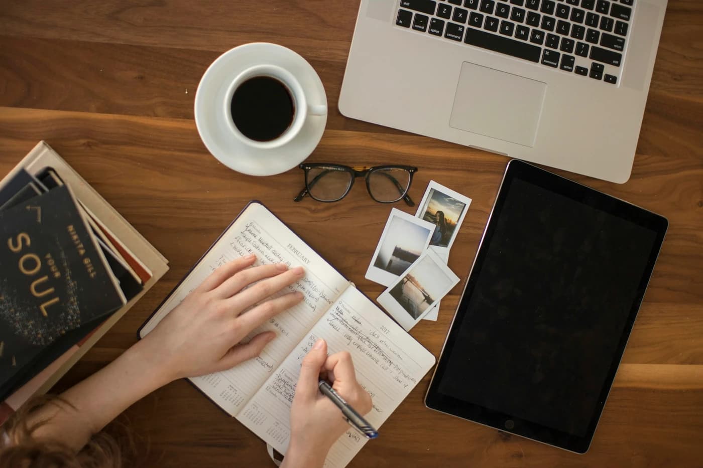 Notebook, photos and a laptop on a wooden desk